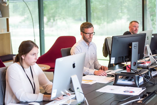 Team members working at desks in an office space, using computer monitors to provide professional automation services